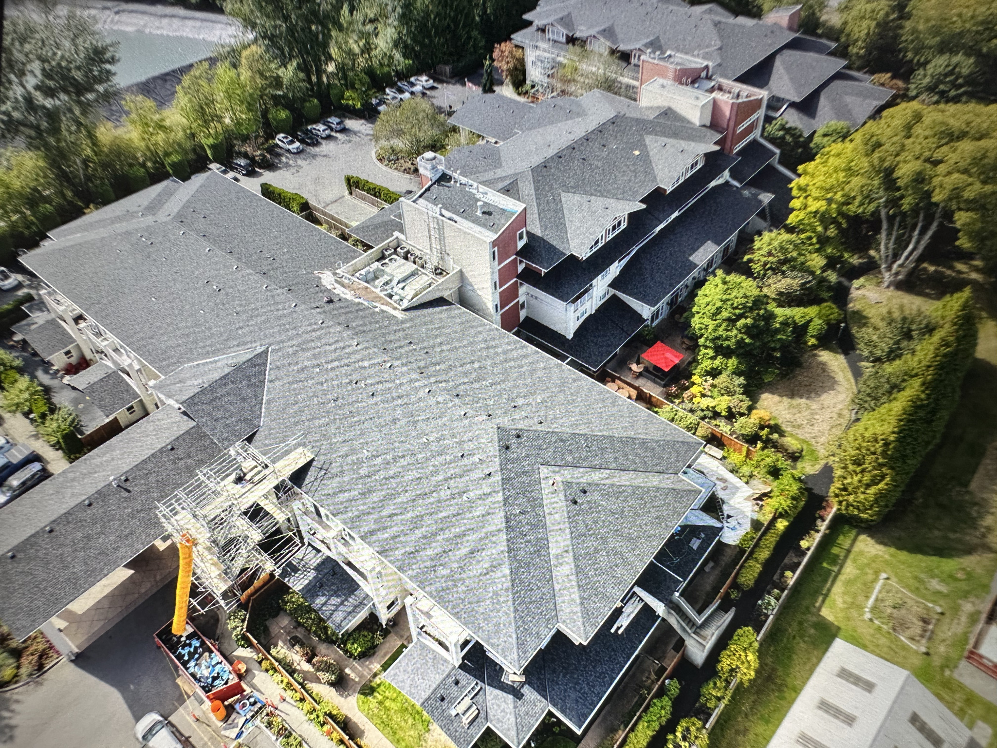 Aerial view of a multi-wing building showing pitched roofs, rooftop equipment and surrounding grounds